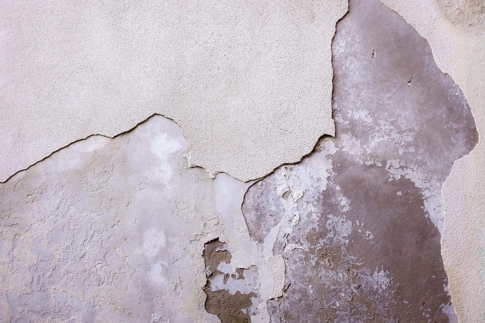 Abblätternde Farb- und Putzschichten an einer alten Wand